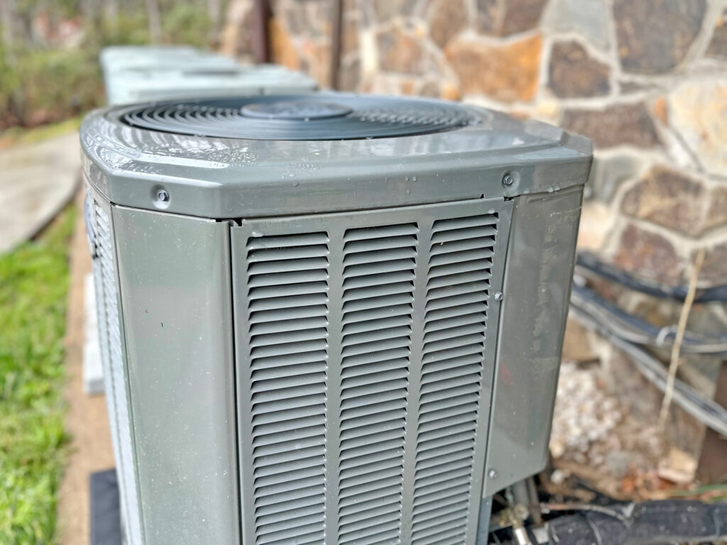 Close-up of AC unit against the side of a house.